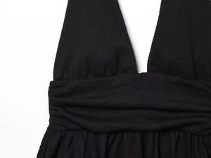Dettaglio del top nero allacciato al collo con scollo a V profondo e trama in tessuto arricciato