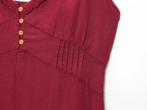 Détail du col en V avec dentelle au crochet et boutons en bois sur robe en lin