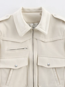 Detailed close-up of cream faux suede jacket featuring silver zippers and shoulder epaulettes