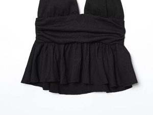 Dettaglio top nero all'americana con bordo a balze e texture in tessuto crepe a pieghe