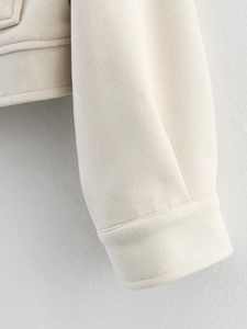 Detail of double stitching and suede texture on light beige jacket cuffs and hem