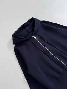 Close-up of a waffle knit hoodie showing metal zipper and textured fabric detail