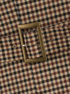 Dettaglio del blazer autunnale pied-de-poule con fibbia in bronzo e cintura in tessuto