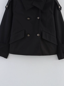 Close-up of black double-breasted trench coat with marble texture buttons and large pockets