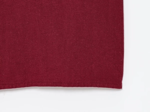 Gros plan détaillé du tissu en lin rouge vin montrant la texture et les coutures