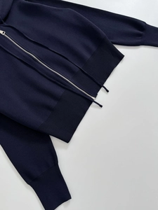Detail of navy blue hooded knitwear showing fine ribbing and silver metal zipper