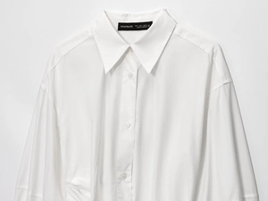 Detailed view of white cotton shirt dress with pointed collar and button-down front