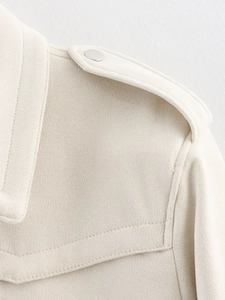 Detail of cream suede jacket shoulder featuring epaulette and silver metal button