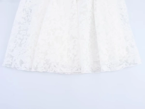 Detail of white hollow-out lace embroidery with elegant floral patterns on dress hem