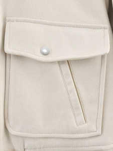Detail of cream suede jacket showing textured fabric, flap pocket and silver button
