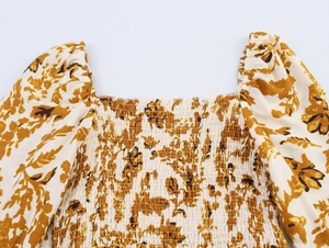Detail of square neckline and smocked chest with floral print on long sleeve dress