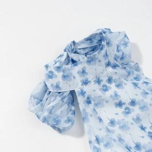 Close-up of light blue floral chiffon fabric with elegant tie-neck detail and soft prints