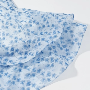 Detail of light blue floral mesh fabric with layered ruffle hem and delicate printing