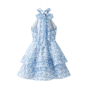 Detail of blue floral smocked dress featuring large bow necktie and tiered skirt design