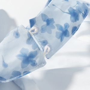 Detailed macro view of V-neckline featuring floral print and delicate button closure