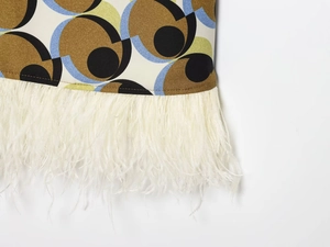 Detail of geometric print fabric with luxurious white ostrich feather trim at the hemline