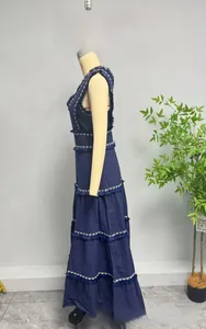 Détail d'une robe longue à volants bleu marine avec franges et motifs géométriques