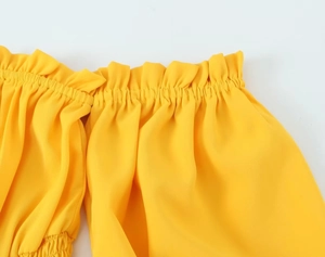 Détail de la robe jaune montrant l'encolure élastique à volants et la texture du tissu