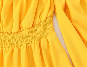 Détail de la taille smockée d'une robe jaune montrant la texture plissée élastique