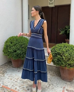 Détail d'une robe longue à plusieurs niveaux avec col en V et broderie bleue et blanche