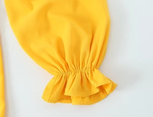 Détail des poignets à volants élastiques et texture de la robe vintage jaune vif
