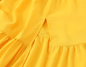 Détail de la robe jaune avec fente et volants soulignant la qualité de couture artisanale