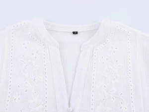 Detailed close-up of white embroidery and hollow-out patterns on the summer shirt