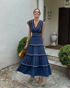 Détail de la broderie florale blanche sur une robe longue à volants bleu foncé sans manches