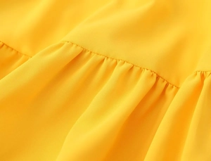 Gros plan détaillé sur les plis froncés d'un tissu en mousseline jaune pour robe d'été