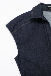 Detailopname van een donkerblauwe denim jurk met gele contraststiksels en een overhemdkraag