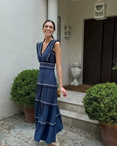 Détail de la robe longue bleu marine à col en V avec broderies blanches et volants