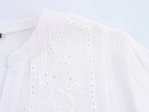 Close-up of white women shirt featuring floral embroidery and eyelet hollow details