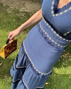 Détail d'une robe bohème bleue avec des épaisseurs de franges et des rubans géométriques