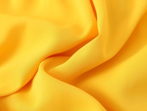 Gros plan détaillé du tissu en mousseline jaune vif avec drapé souple et texture sablée