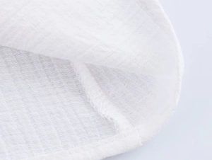 Detailed close-up of white fabric texture and neat stitching on a long-sleeve blouse