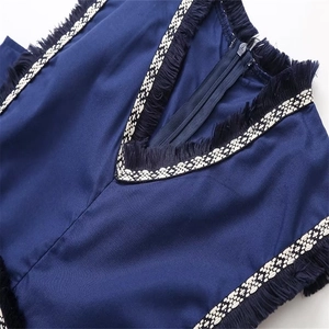 Détail du col en V avec broderie contrastée et franges noires sur robe bleu marine