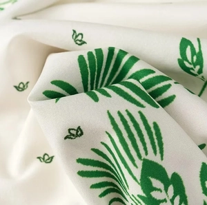 Detailaufnahme von weichem weißem Stoff mit frischem grünem Pflanzen- und Blumenmuster