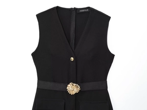 Detail of black crepe midi dress featuring gold spiral floral buckle and V-neck line