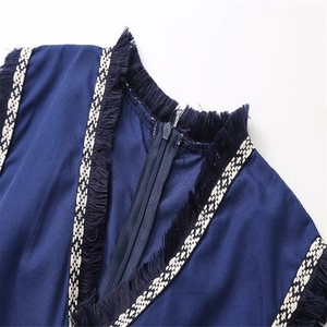 Détail du col en V avec franges bleu marine et broderie géométrique sur la robe