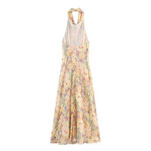 Detailed close-up of vibrant floral print on yellow halter backless maxi dress