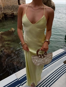 Detail of light yellow satin midi dress with cross straps and elegant V-neckline