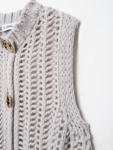 Detail view of light gray chunky knit cardigan featuring gold textured buttons and patterns
