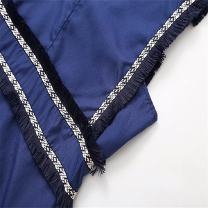 Détail du tissu bleu marine avec franges noires et ruban à carreaux noir et blanc