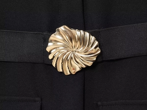 Detailed close-up of golden spiral metal buckle on textured black crepe fabric