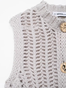 Detail of light gray chunky knit sweater with hollow texture and gold hammered buttons