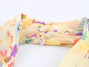 Close-up of floral print dress featuring twist pleated fabric and three white buttons