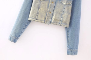 Detail of blue denim jacket featuring a unique metallic gold coating and chest pockets