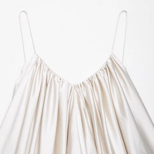 Detail of cream satin top with thin straps, deep V-neck and elegant ruched textures