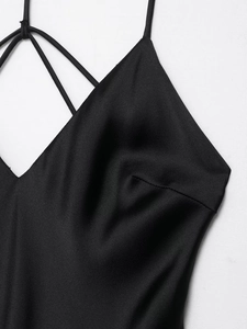 Detail of satin slip dress featuring elegant V-neckline and delicate crossover straps