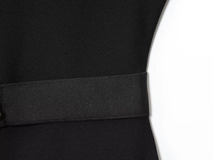 Detail of black crepe midi dress showing wide elastic waistband and honeycomb fabric texture